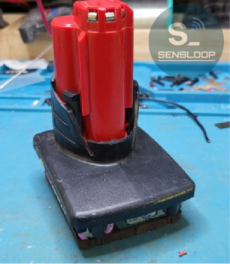 수리가 완료된 밀워키 M12 배터리팩을 최종 조립하여 외형을 점검하는 모습.